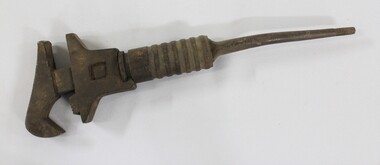Large cast iron shifter wrench with an adjustable grip and a circular turning mechanism at the top of a thin tapering handle.