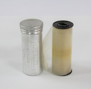 A clear film roll beside a metal film tin 