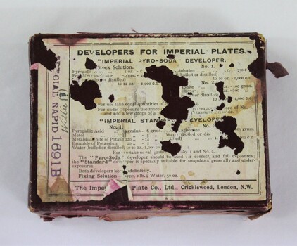 A burgundy coloured cardboard box with technical and manufacturers information printed on white paper on lid 