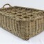 Rectangular wicker crate for delivering bottled drinks with 12 compartments and handles at each narrow end.