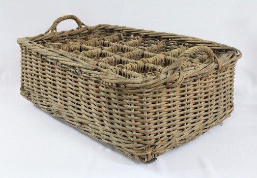 Rectangular wicker crate for delivering bottled drinks with 12 compartments and handles at each narrow end.