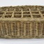 Rectangular wicker crate for delivering bottled drinks with 12 compartments and handles at each narrow end.