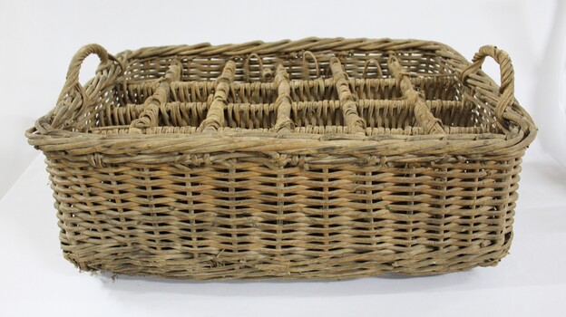 Rectangular wicker crate for delivering bottled drinks with 12 compartments and handles at each narrow end.