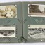 An open photograph album showing a black and white photograph and three postcards.