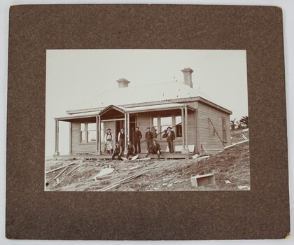 A group of men standing in front of a newly erected timber house 