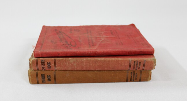 Three red cloth bound books stacked vertically. 