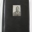 A black photographic album with a photograph of a man inserted into the front cover