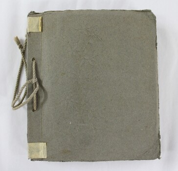 Front cover of the photograph album showing an embossed floral motif and cotton rope binding of the album spine