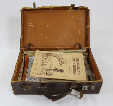 A brown vinyl suitcase containing song books, periodicals and magazines  
