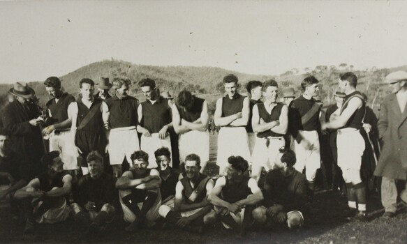 A black and white group portrait photograph of a male AFL team dressed in football uniform