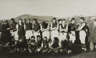 A black and white group portrait photograph of a male AFL team dressed in football uniform