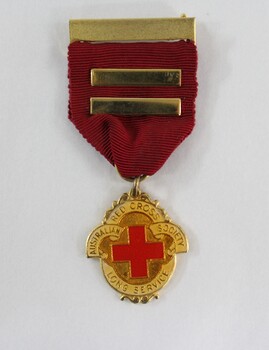 A gold tone metal badge on a red ribbon 