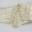 A cream coloured dip-waist belt with reserve showing metal clasp 