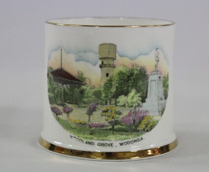 White cup with a gold rim and gold trim around the base. A hand-coloured transfer image fills the front side