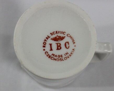 Maker's mark for IBC Royal Scenic China. Orange circular text with crown in centre and initials IBC