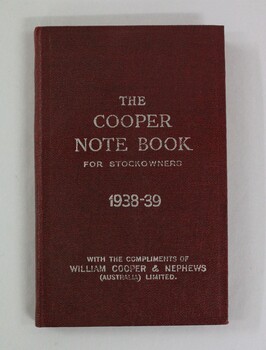 A small red cloth bound note book with white embossed text