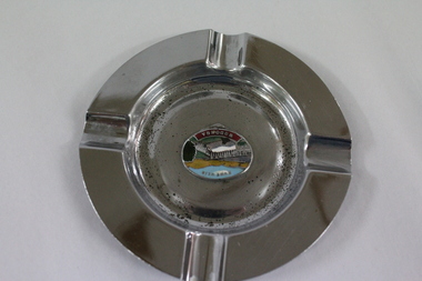 A circular metal ashtray, featuring an image of the Hume Weir in the centre.