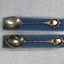 Two souvenir teaspoons in a clear plastic case. Top of each spoon bears the badge of the Rural City of Wodonga, Victoria