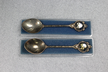 Two souvenir teaspoons in a clear plastic case. Top of each spoon bears the badge of the Rural City of Wodonga, Victoria