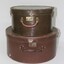 Two brown hat boxes, one small and one large 