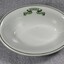 An oval shaped bowl with dark green trim and logo