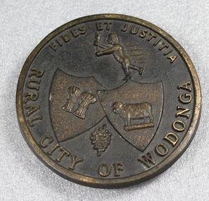 Circular plate from the Rural City of Wodonga. Includes symbols of cattle, wheat and grapes, the mythological figure Hermes/Mercury and the Latin "Fides et Justitia"