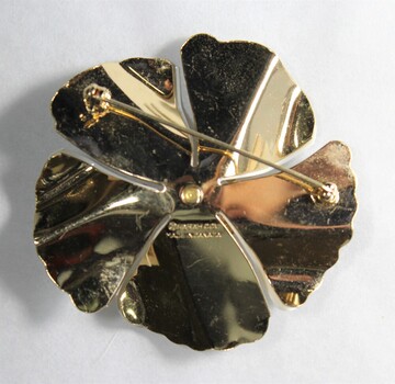 Back of a white and gold-toned brooch in the shape of a flower from the Sarah Coventry Pty. Ltd. jewellery range.