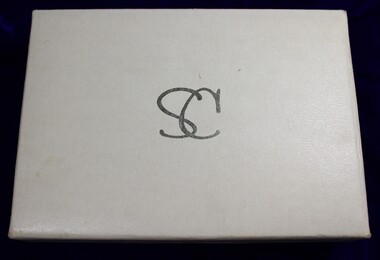 Top of white jewellery box inscribed with intertwined silver letters SC