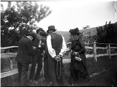 Four men inspecting fruit on the Haeusler property, with a woman looking on