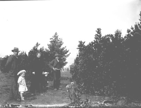 A woman, two men and two children with dogs in the foreground on the right.