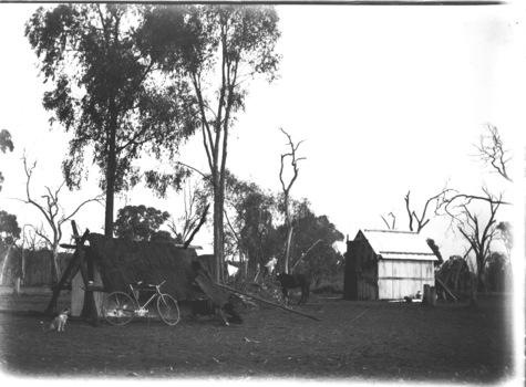 A tent on the left of the image with a bicycle leaning in front of it. Another building on the right of the image.