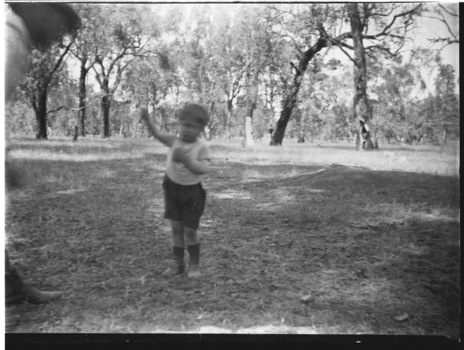 Small child in Wodonga West, Victoria. A man stands at the left hand side of the image.