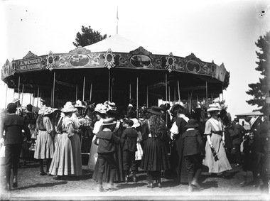 A large group of people standing around a steam carousel