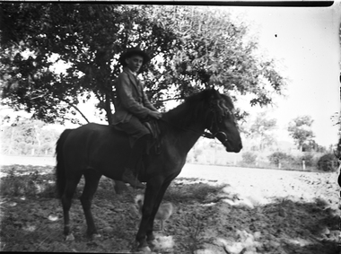 An unidentified man on horseback. There is a small dog standing beside them.