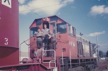 3 railways staff standing on the front of a diesel pilot train.