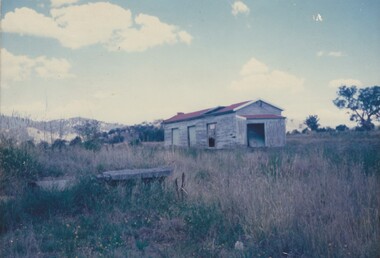 Remains of an abandoned railway shed in open paddock.