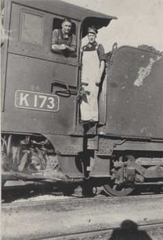 2 railway men standing on the steps of a locomotive