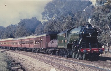 "The Flying Scotsman" locomotive hauling train with forest in the background.