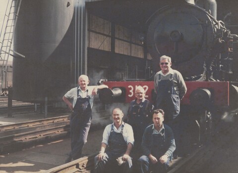 5 railway men standing in front of a locomotive