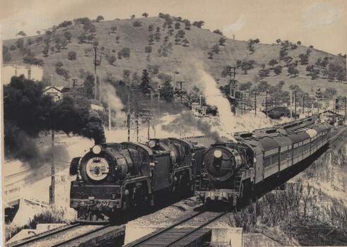 2 locomotives side by side with hills in background