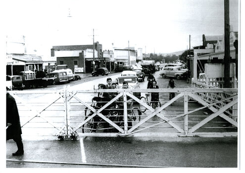 Cars and cyclists waiting at the closed level crossing gates.