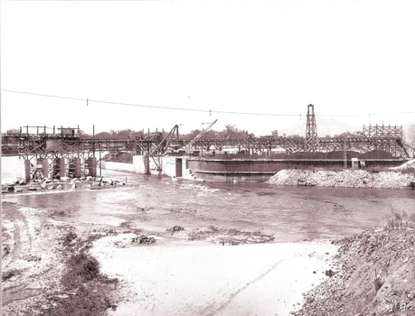 Section of completed coffer dam with river diverted over the concrete foundations of dam.