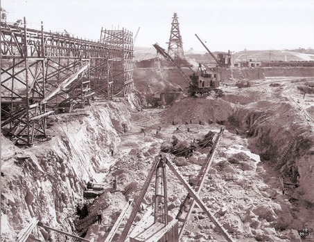 Excavations, machinery and workmen inside coffer dam.