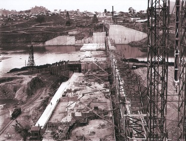 View of concrete dam from top of tall tower pillar. 