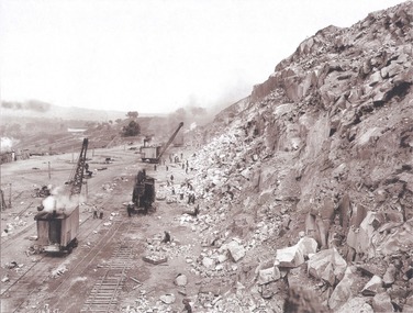  View along the face of the quarry with machinery and workmen.