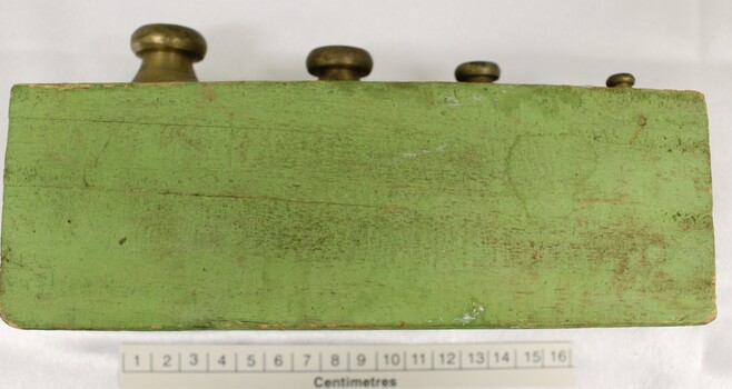 Side view of set of metric weights in holder with scale in centimetres