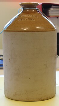 Tall ceramic demijohn with business name of R.C. Phillips inscribed on the tan top section