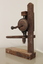 Metal hand drill attached to wooden stand