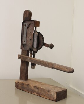 Back view of hand drill mounted on wooden stand
