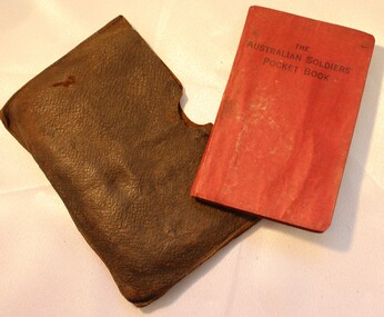  Brown leather wallet on the left and red-covered Australian Soldiers' Pocket Book on right.